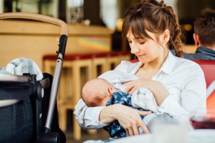 A mother breastfeeding baby in a cafe
