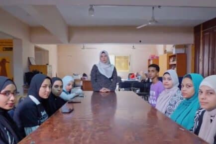 Women wearing hijabs sitting at a long table.