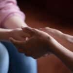 Two people holding hands in show of support. Stock image.