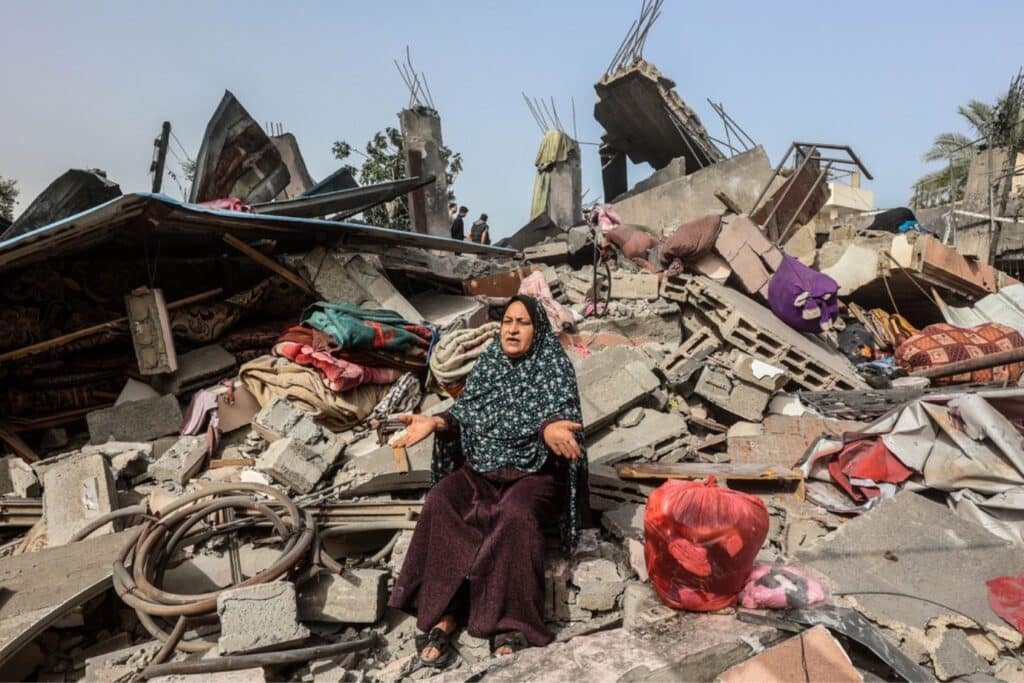 Woman sitting amongst rubble of destroyed building