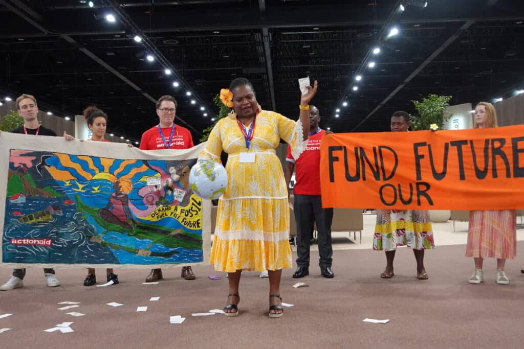 On Finance Day at COP28 members of the ActionAid delegation take part in an action demonstrating how banks are pouring finance into fossil fuel production.