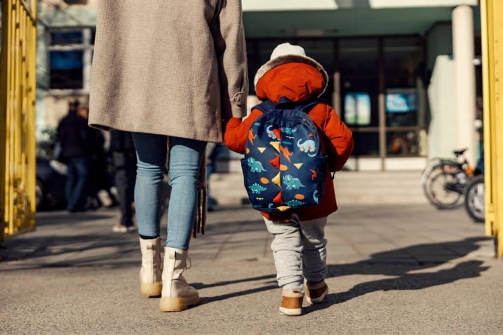 Woman holding child's hand, walking to daycare