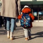 Woman holding child's hand, walking to daycare