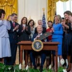 Joe Biden signing executive order for investment in women's health, surrounded by women at the White House, Washington DC