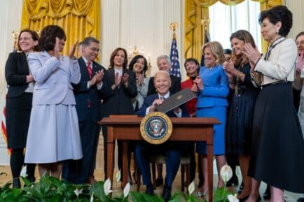 Joe Biden signing executive order for investment in women's health, surrounded by women at the White House, Washington DC