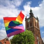 LGBTQIA+ flag flying in front of religious building