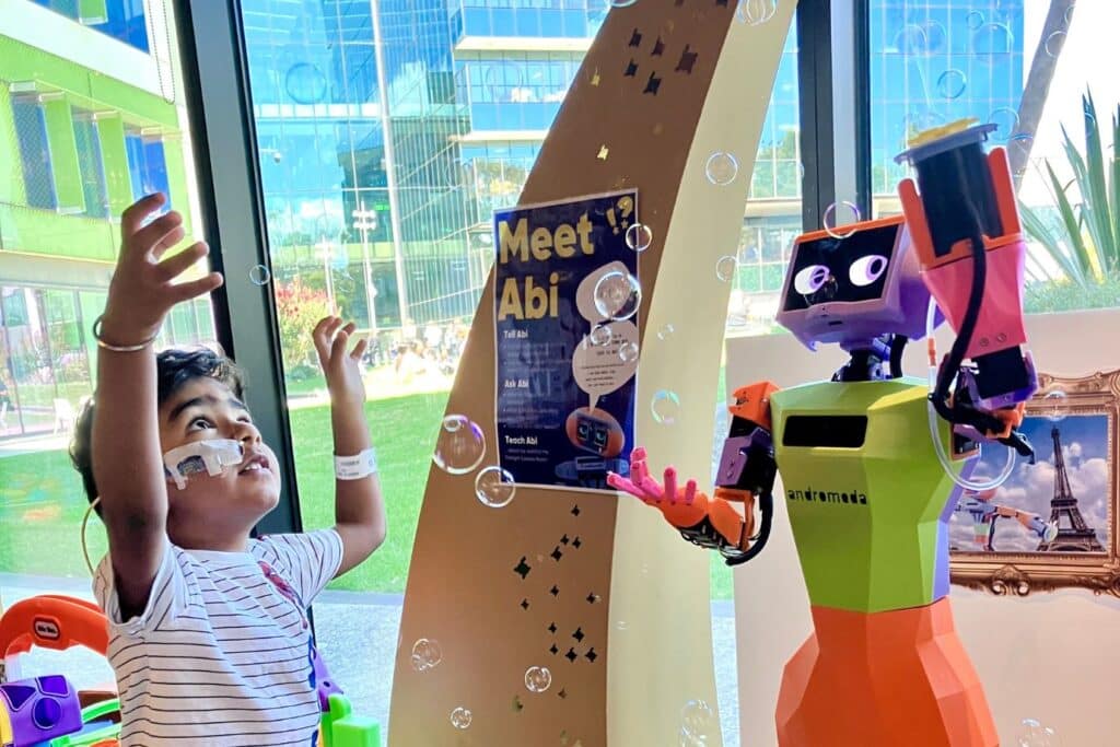 Young boy playing with Andromeda's humanoid robot, abi